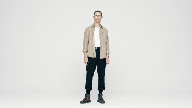 Full length of a young caucasian man looking at camera. Stylish man standing on white background.