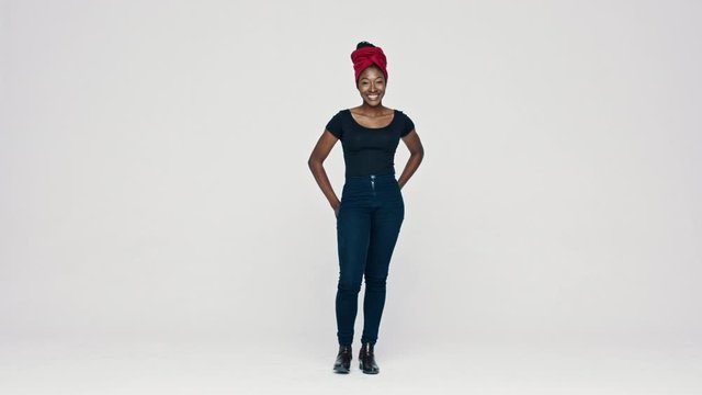 Full length of a smiling African woman standing on white background with her hand on hips. African female with a cloth wrapped on head looking at camera.