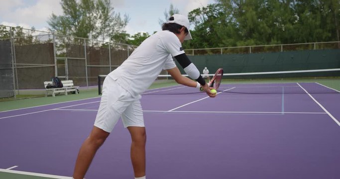 Man serving tennis ball on purple court