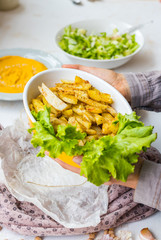 Homemade golden salty french fried potato with green salad leaves. Roasted or grilled spicy potato sticks.