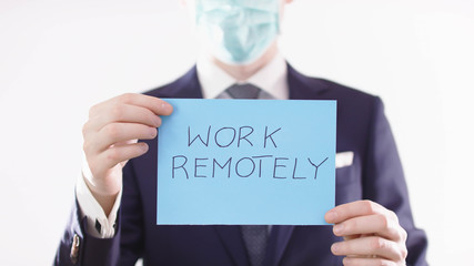 Work remotely. Businessman with medical mask advising to work from home