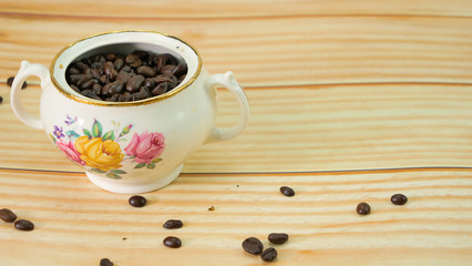 Des grains de café dans un bol rustique antique sur une table en bois naturel