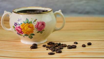 Des grains de café dans un bol rustique antique sur une table en bois naturel