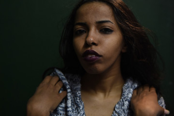 young african woman posing at studio, face with hand portrait over dark background	