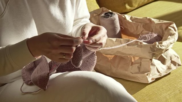 Woman knitting thread from the package of balls of yarn on a sunny day