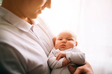 Portrait of a newborn baby. Father holds a child in her arms. The first year of life. Care and health