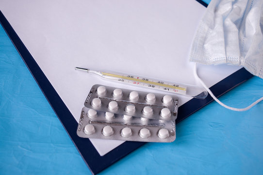 Prescription tablet, medical mask, tablets, thermometer on a blue background