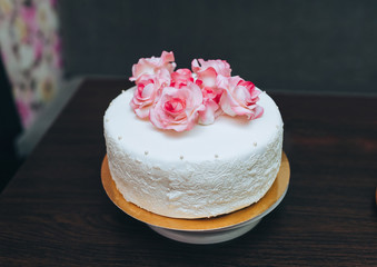 Obraz na płótnie Canvas A single tier white wedding cake with pink rose flowers from a pastry glaze.