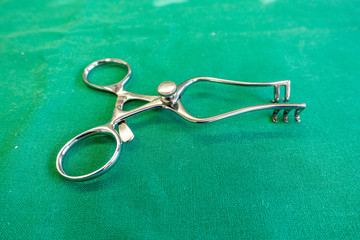 on a green surgical sheet lies a surgical retractor