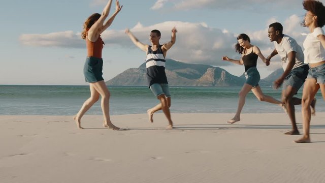 Group of multi-ethnic friends running and enjoying on the beach. Carefree young people having a great time together on a vacation.