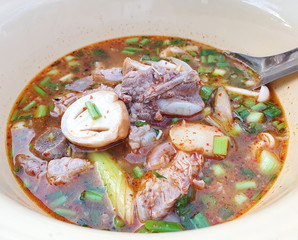 Spicy pork spare rib soup with served in a white bowl with a spoon. Pork tom yum with straw mushrooms and many herbs such as lemongrass, chilli, galangal,spring onion, lemon. It is a popular Thai food