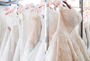 Beautiful, White bridal dress texture on background. Wedding dresses hanging on a hanger interior of bridal salon. Design, fashion modern luxury in detail.