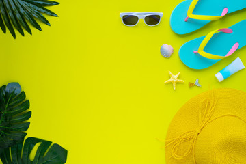 Fototapeta na wymiar Summer holiday of traveler women. Top view from above of beach accessories and a hat with sunglasses and sandals on yellow background. Flat lay with copy space. Tropical fashion vacation concept.