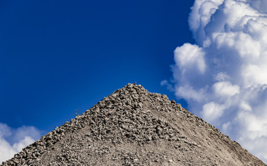 Kieshaufen mit blauem Himmel und Wolken