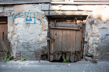 An old wooden door, a closed hanging lock and a broken brick wall