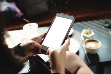 Mockup image of a woman holding and showing black mobile phone with blank screen in cafe