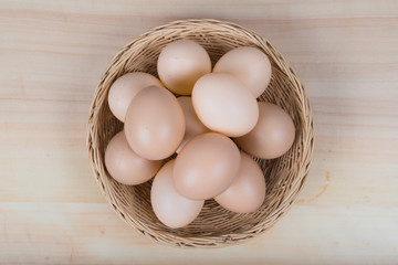 Several eggs were placed in a wooden basket on a wooden table.