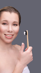 Obraz premium Girl hold wood toothbrush with toothpaste. Oral home routine. Bamboo eco brush. Smiling woman. Plastic free health care. Manual dentist hygiene. Happy female person morning