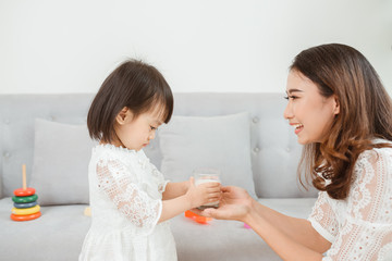 Young beautiful mother preparing milk for her daughter at home.