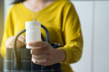 Hands woman holding a medicine pills bottle into handbag