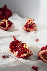 Pieces of ripe pomegranate fruit lie on a table on a white wooden background. Juicy fresh pomegranates. Organic Fruits