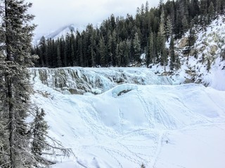 Fototapeta na wymiar A winter setting of a frozen waterfall surrounded by forests and mountains at wapta falls, yoho national park, british columbia, canada