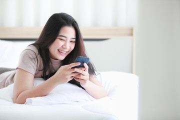 Woman using telephone on bed in bedroom.