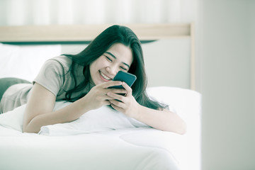 Woman using telephone on bed in bedroom.