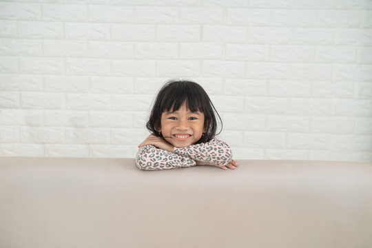 Happy Excited Asian Young Girl Head Peeping From Behind The Sofa