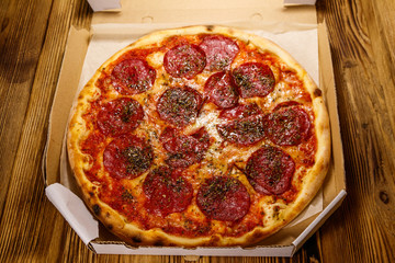 Delicious fresh pizza in cardboard box on a wooden table. Concept for home delivery of food, fast food, delivery of pizza