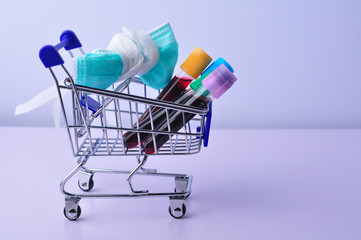 Medical mask and test tube with blood on shopping cart with white background. Concept of shopping health care products.