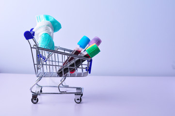 Medical mask and test tube with blood on shopping cart with white background. Concept of shopping health care products.