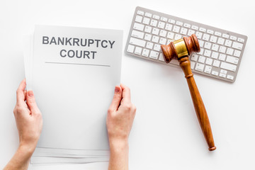 Bankruptcy court concept with document in hands and gavel on white background top-down
