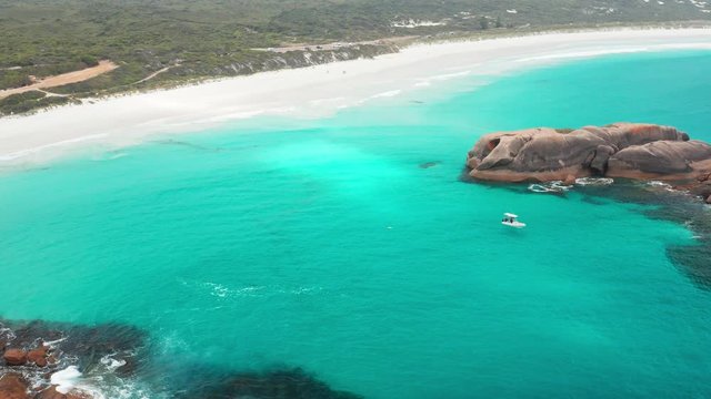Pull away aerial shot of coast watch crew checking for sharks in a small boat near the beach and rocks around Twilight Cove, Esperance, Western Australia