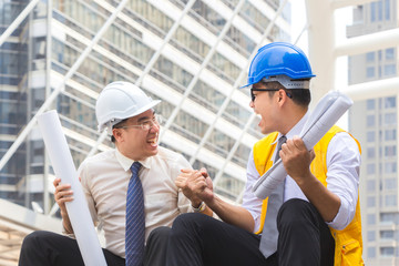 Success and Happiness concept, Business engineer man holding drawing paper in hand at city outside office.