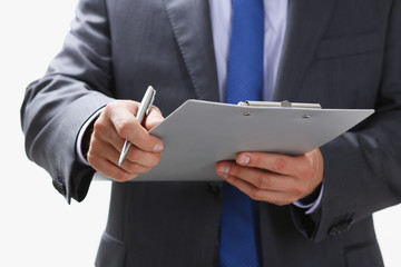 Hand of businessman in suit filling and signing with silver pen partnership agreement form clipped to pad closeup. Management training course some important document team leader ambition concept