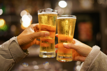 Two men clink glasses of whiskey drink alcoholic beverage together while at bar counter in the pub,Substance abuse