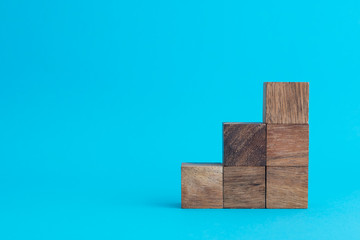Wooden cube block stacking as stair or graph on blue background with copy space. Concept of business and financial strategy, planning for success growth KPI target.