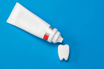 The toothpaste is applied from a tube to the figure of the tooth on a blue background.