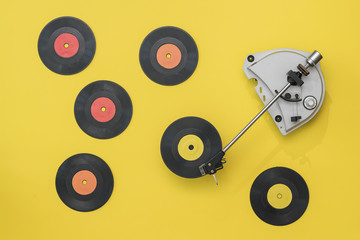 Vintage record player with multi-colored vinyl discs on a yellow background.