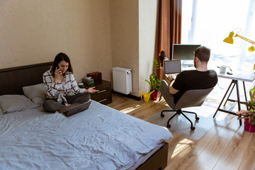couple working at home. home isolation. woman on bed. man at office chair