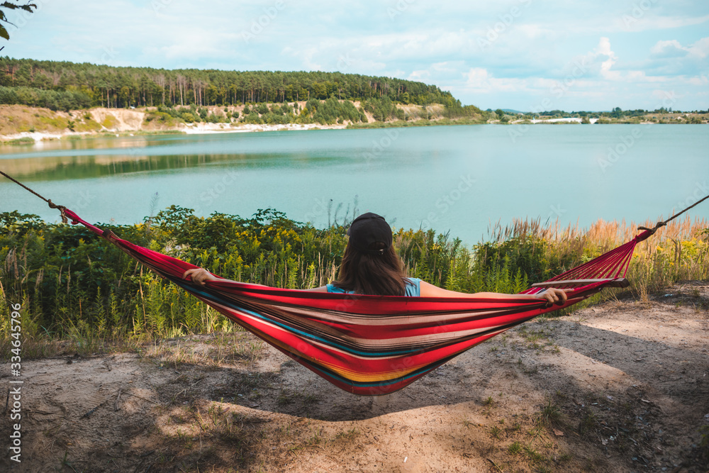 Poster woman laying on hammock enjoying the view of summer lake