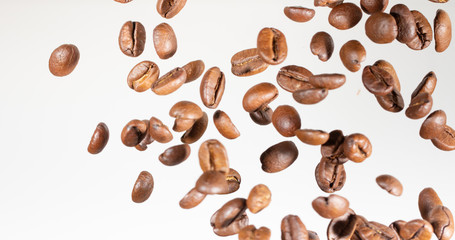 Falling coffee beans, in motion, on a white background. Selective focus.