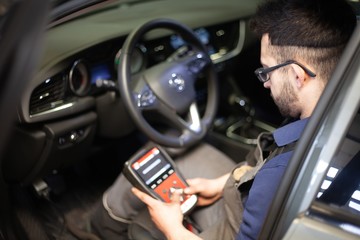 man calibrating car tires with computer in mechanics garage