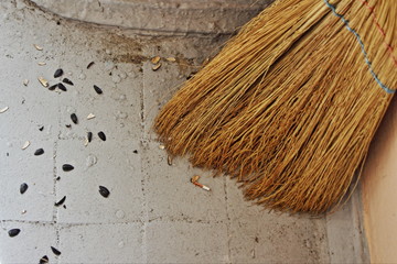 Broom close-up near the husk of seeds on the floor, cleaning in public places