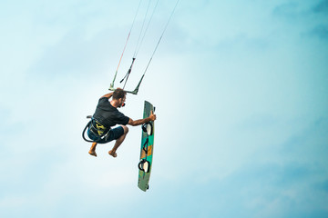 Kiteboarder or kite surfer. Man performing kitesurfing kiteboarding tricks. Ocean sport.