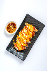 Gyoza or dumplings topped with cheese sauce and soy sauce on white isolated