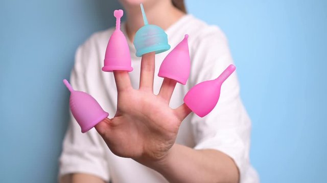 Woman hand holding menstrual cup. Different menstrual cups, comparison. Alternative feminine hygiene product during the period. Zero waste concept