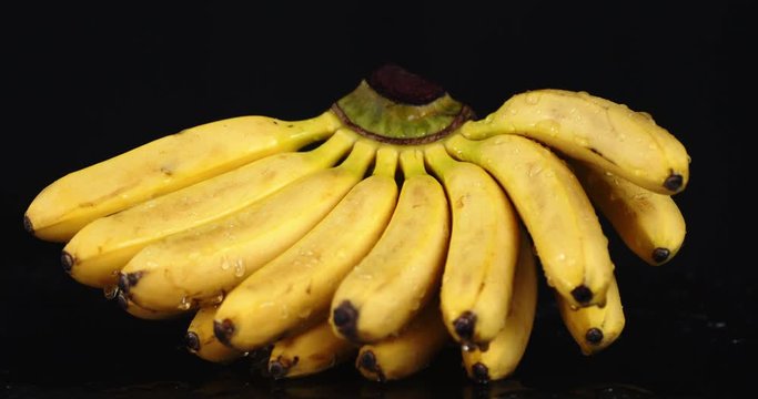 A bunch of bananas with water drops rotates slowly.