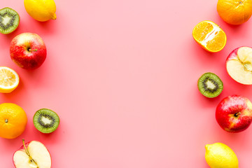 Oranges, lemon, apple, kiwi and grape - healthy food concept with fruits - on pink background top-down frame copy space